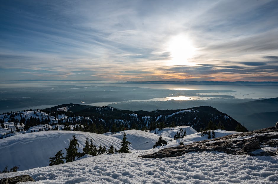 A sunset over snowy mountains and a distant sea